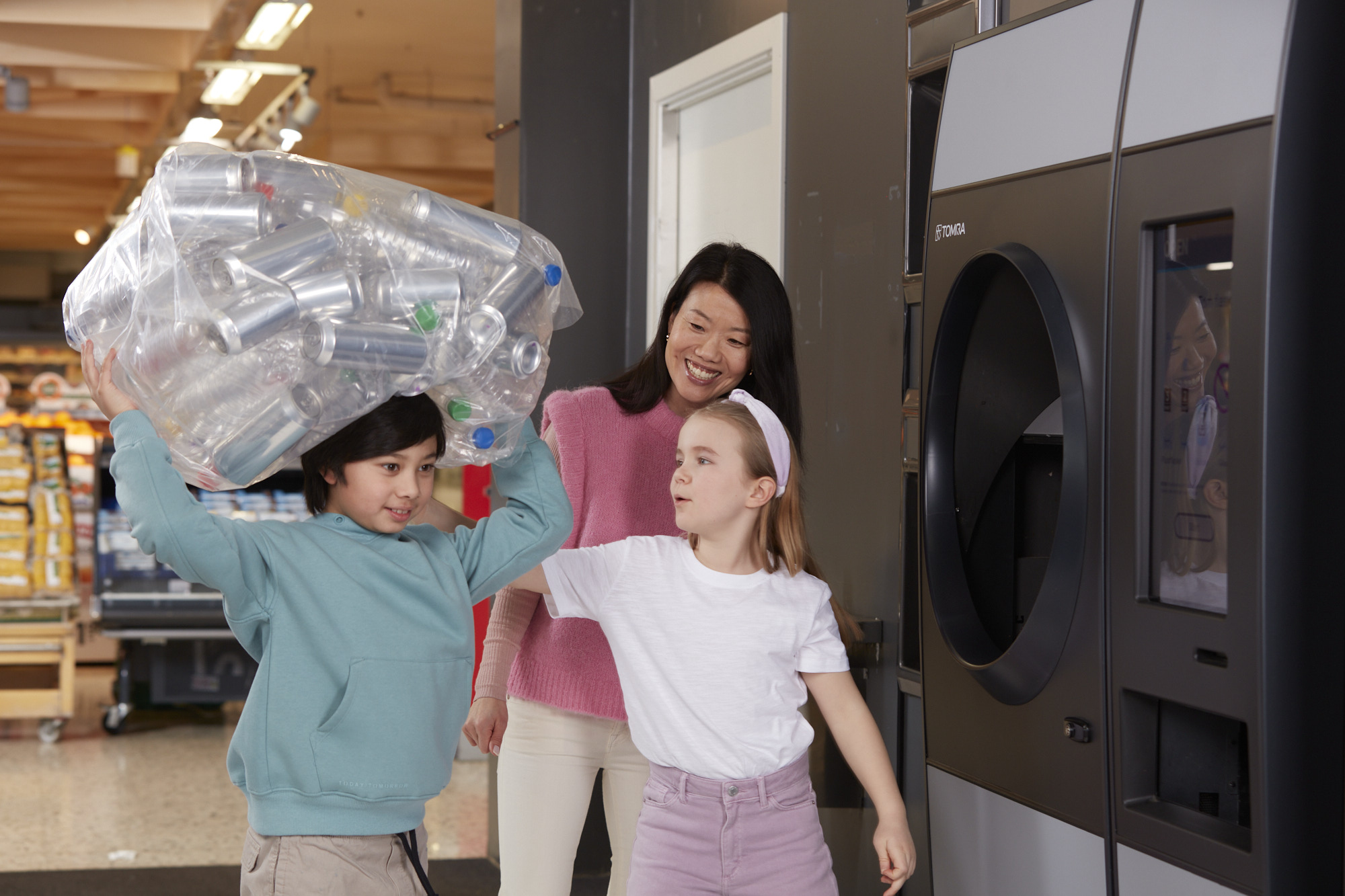 Photo d'enfants et d'une adulte recyclant devant un automate de déconsigne