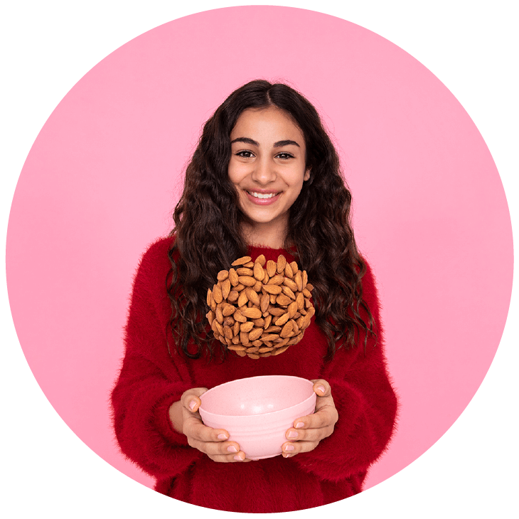 Woman holding a bowl from which almonds have been tossed up