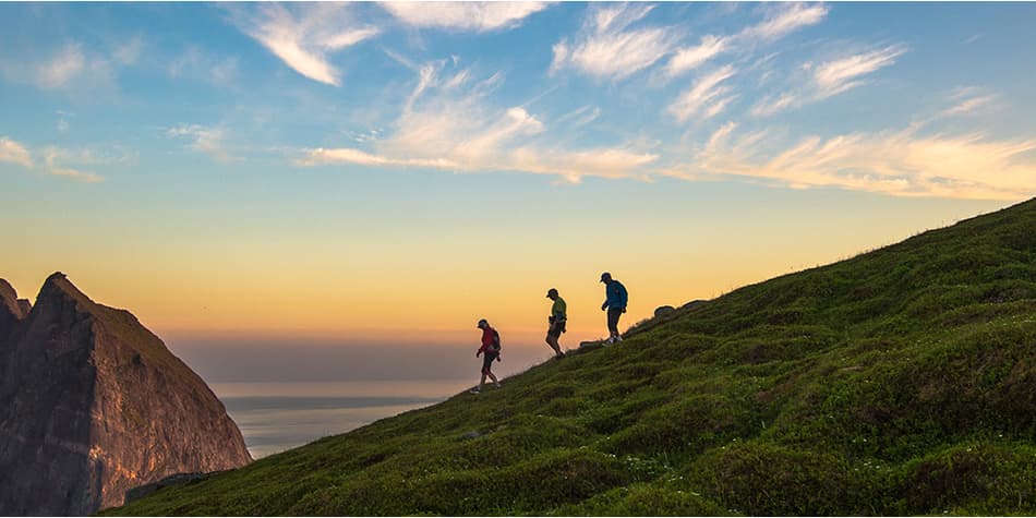 Three people walking on mountain ridge